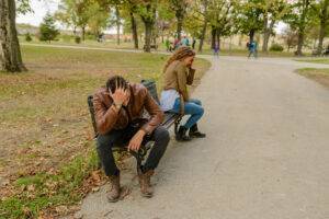 Image of couple on park bench, head in hands facing away from eachother