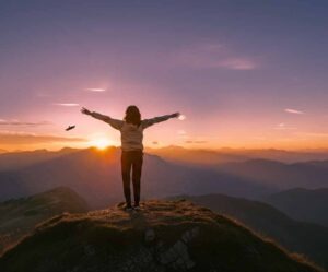 Image of woman on mountain arms open towards sun
